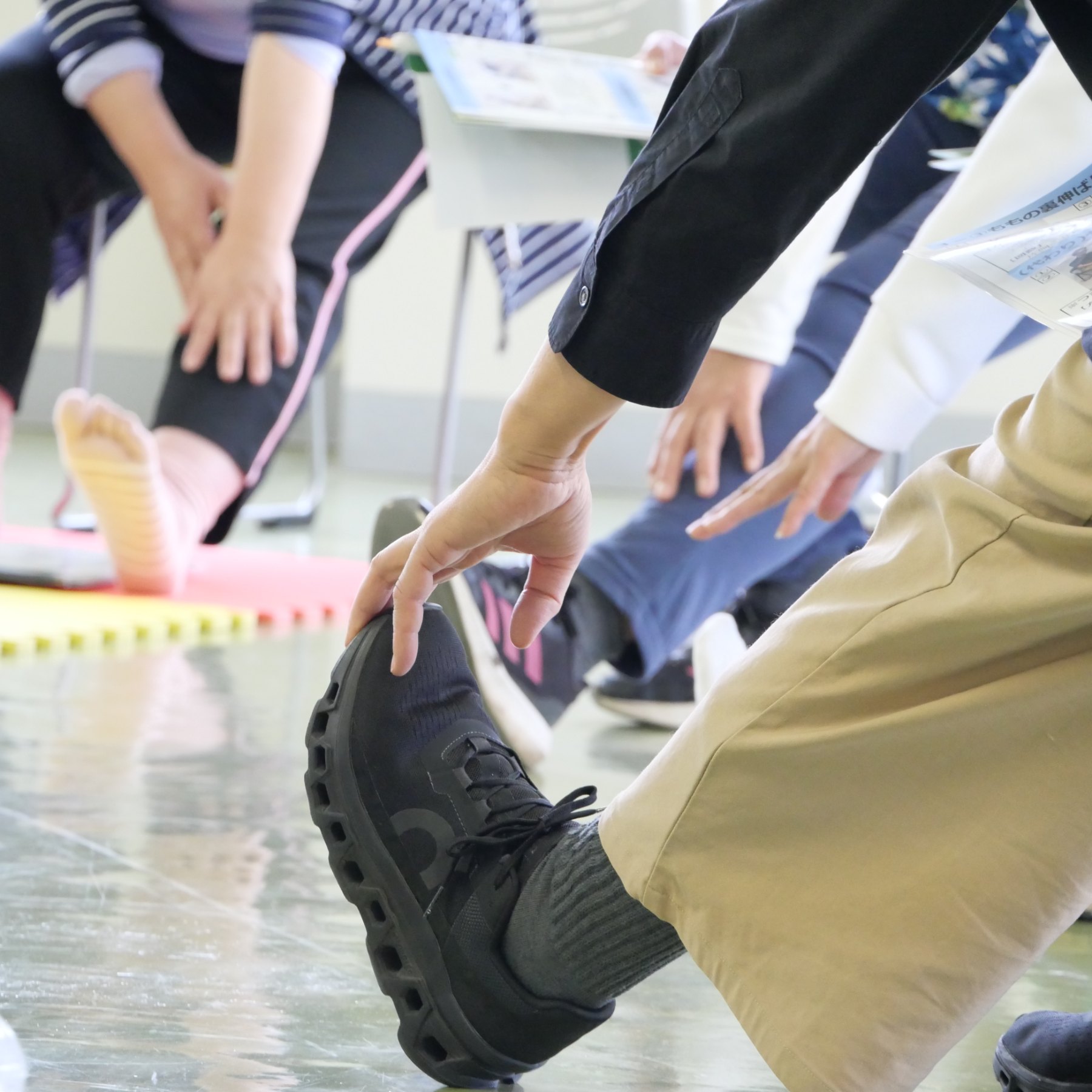 石巻市での健康教室。地域の参加者が円になり、両手を高く上げて体操をしている。