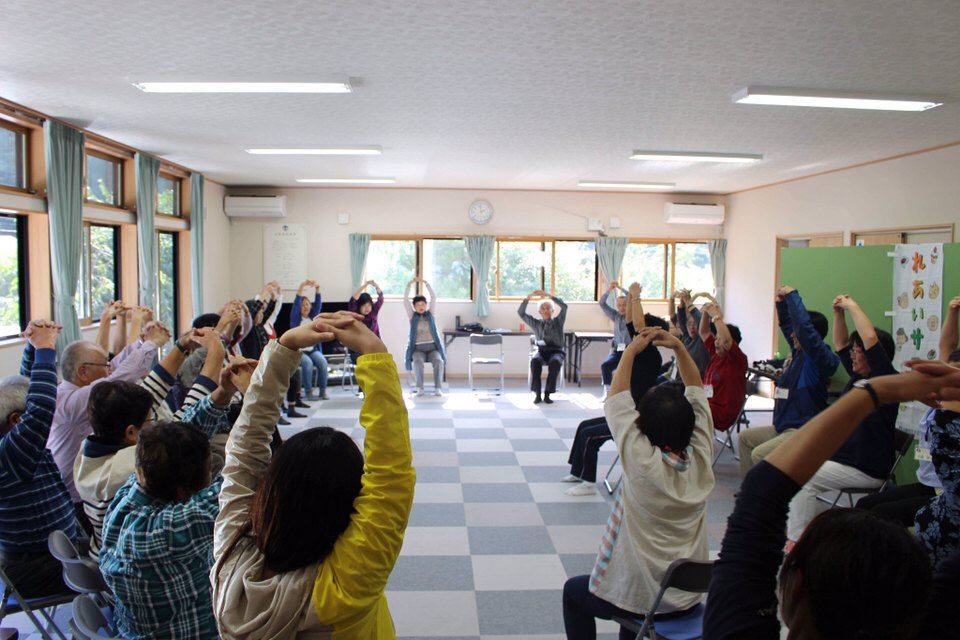窓際で体操をする地域の参加者たち